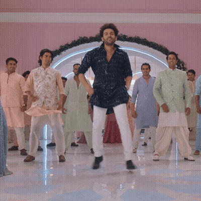 A Man In A Blue Shirt Is Dancing With A Group Of Men In White Pants GIF