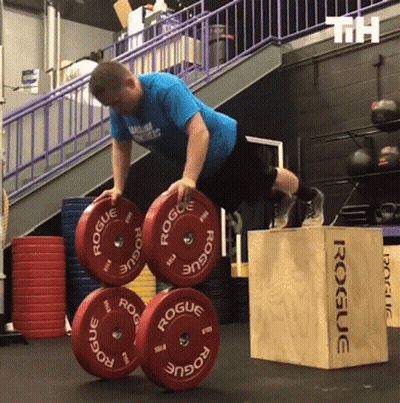 A Man In A Blue Shirt Is Doing Push Ups On Rogue Weights GIF