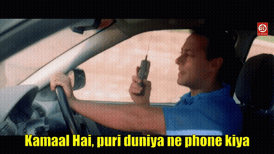 A Man In A Blue Shirt Is Driving A Car While Holding A Cell Phone GIF