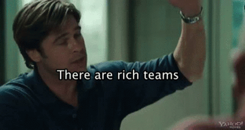 A Man In A Blue Shirt Is Giving A High Five With The Words `` There Are Rich Teams '' Behind Him . GIF