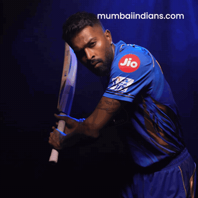 A Man In A Blue Shirt Is Holding A Bat And The Website Mumbaiindians.com Is Visible Behind Him GIF