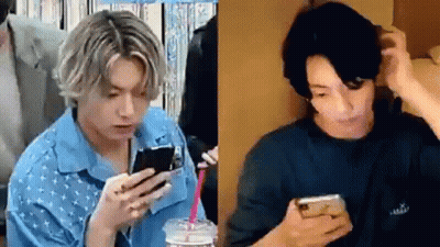 A Man In A Blue Shirt Is Holding A Cell Phone In His Hand . GIF