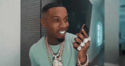 A Man In A Blue Shirt Is Holding A Cell Phone In His Hand . GIF