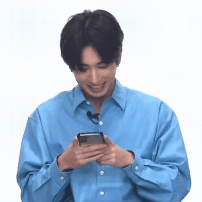 A Man In A Blue Shirt Is Holding A Cell Phone In His Hands . GIF