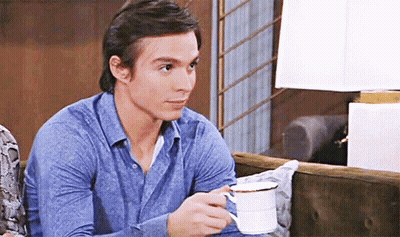 A Man In A Blue Shirt Is Holding A Cup Of Coffee . GIF