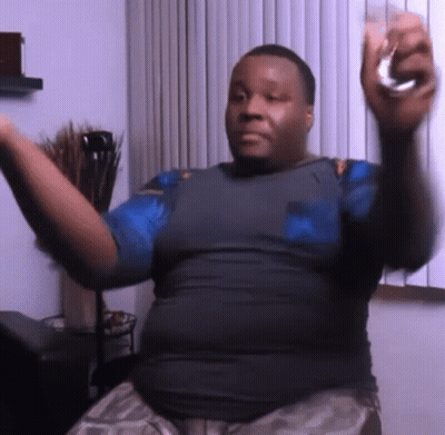 A Man In A Blue Shirt Is Holding A Glass In His Right Hand GIF
