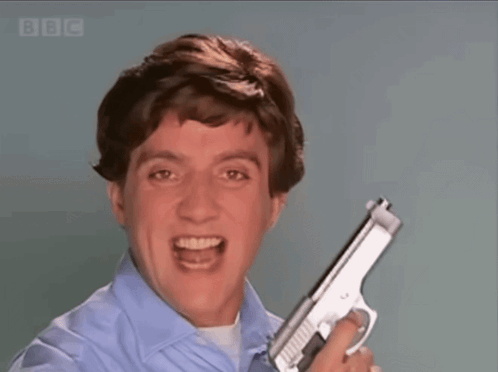 A Man In A Blue Shirt Is Holding A Gun In Front Of A Screen That Says Bbc GIF
