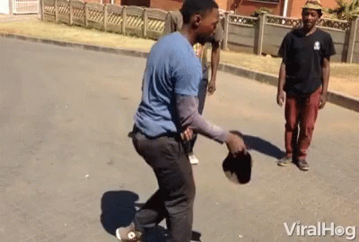 A Man In A Blue Shirt Is Holding A Hat While Another Man Watches GIF