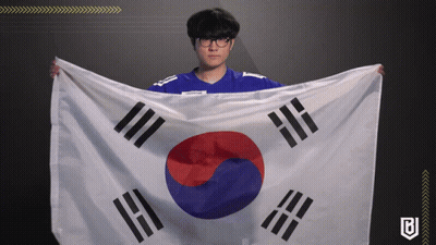 A Man In A Blue Shirt Is Holding A Korean Flag In His Hands GIF