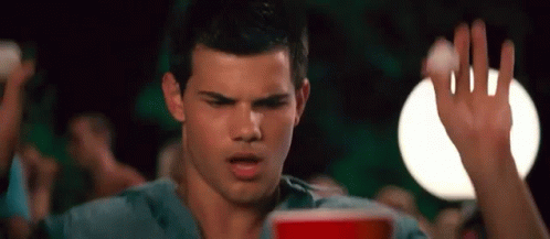 A Man In A Blue Shirt Is Holding A Red Cup In His Hand . GIF