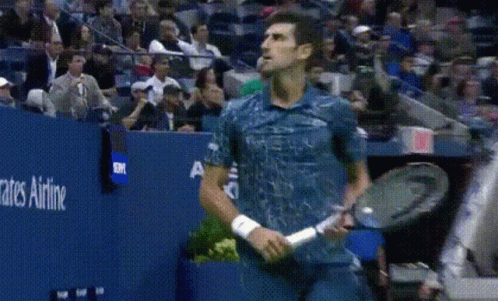 A Man In A Blue Shirt Is Holding A Tennis Racquet In Front Of A Sign That Says Rates Airline GIF
