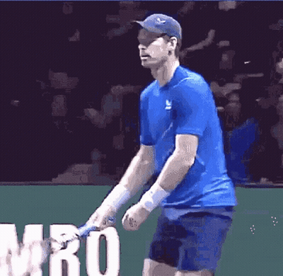 A Man In A Blue Shirt Is Holding A Tennis Racquet In Front Of The Word Mro GIF