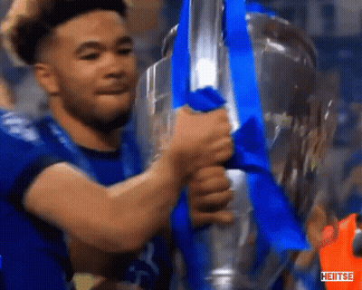 A Man In A Blue Shirt Is Holding A Trophy With A Blue Ribbon And The Word Heiitse On The Bottom GIF