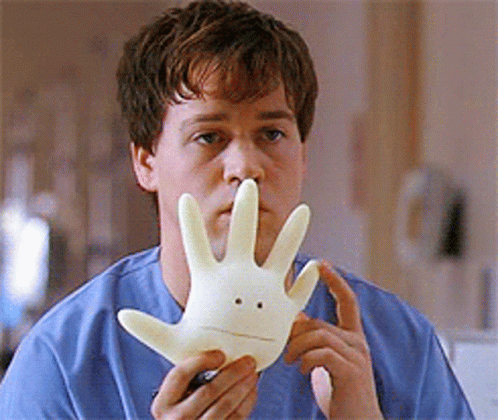 A Man In A Blue Shirt Is Holding A White Hand With A Face On It GIF