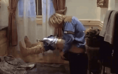 A Man In A Blue Shirt Is Holding A Woman 'S Leg In A Room . GIF