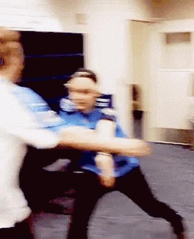 A Man In A Blue Shirt Is Holding Another Man 'S Arm GIF
