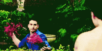 A Man In A Blue Shirt Is Holding Flowers In His Hands GIF