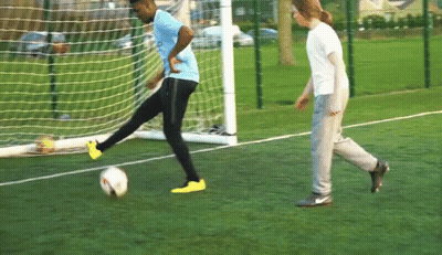 A Man In A Blue Shirt Is Kicking A Soccer Ball In Front Of A Goal GIF