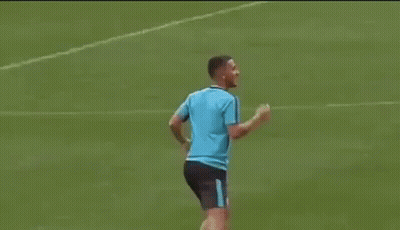 A Man In A Blue Shirt Is Kicking A Soccer Ball On A Soccer Field . GIF