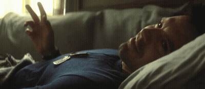 A Man In A Blue Shirt Is Laying In Bed With His Eyes Closed GIF
