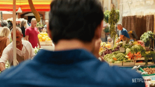 A Man In A Blue Shirt Is Looking At A Market With A Netflix Logo On The Bottom Right GIF