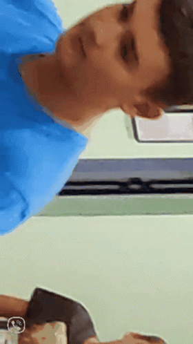 A Man In A Blue Shirt Is Looking At Something GIF
