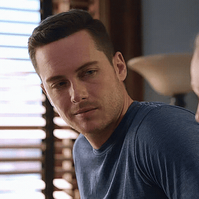 A Man In A Blue Shirt Is Looking At The Camera . GIF