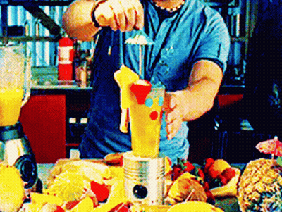 A Man In A Blue Shirt Is Making A Drink With A Blender GIF