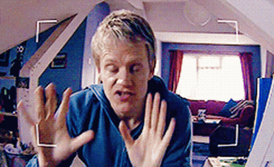 A Man In A Blue Shirt Is Making A Funny Face In Front Of A Camera GIF