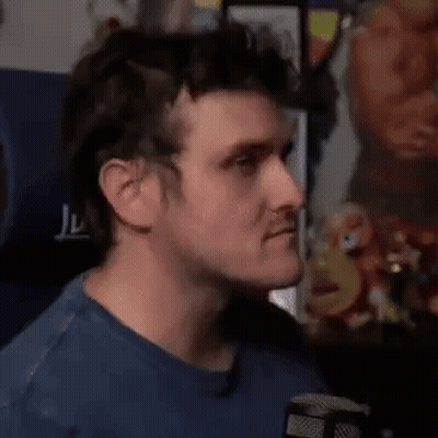A Man In A Blue Shirt Is Making A Funny Face While Holding His Finger To His Lips . GIF