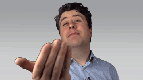 A Man In A Blue Shirt Is Making A Funny Face With His Hand GIF