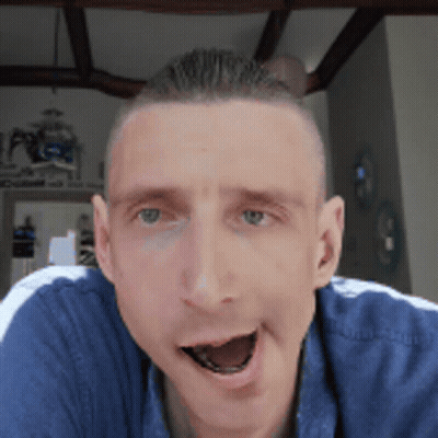 A Man In A Blue Shirt Is Making A Funny Face With His Mouth Open GIF