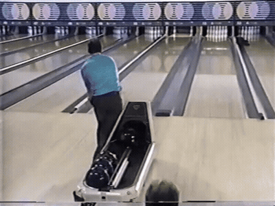 A Man In A Blue Shirt Is Playing Bowling On A Bowling Alley GIF
