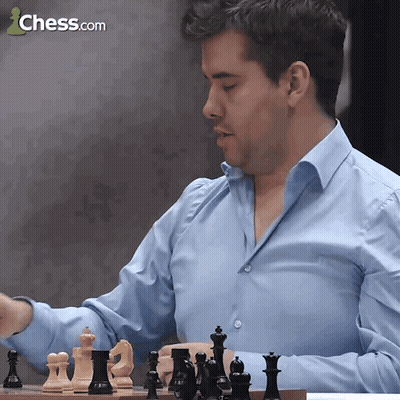 A Man In A Blue Shirt Is Playing Chess With A Chess.com Logo In The Background GIF