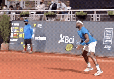 A Man In A Blue Shirt Is Playing Tennis On A Court With A Bci Logo On The Wall Behind Him GIF