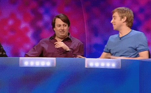 A Man In A Blue Shirt Is Pointing At Another Man In A Purple Shirt GIF