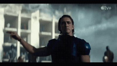 A Man In A Blue Shirt Is Pointing At Something In Front Of A Building In A Movie . GIF