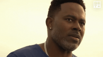 A Man In A Blue Shirt Is Praying With His Hands Folded In Front Of His Face GIF