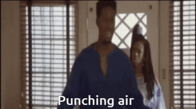 A Man In A Blue Shirt Is Punching Air While A Woman Stands Behind Him . GIF