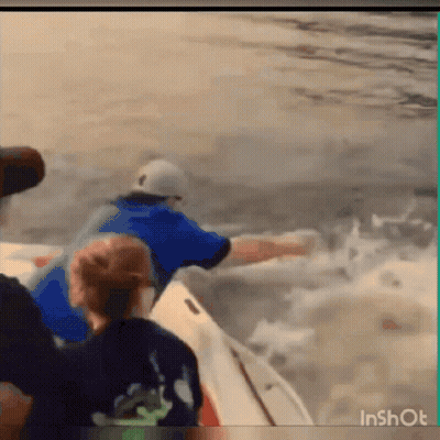 A Man In A Blue Shirt Is Riding A Boat In The Ocean . GIF