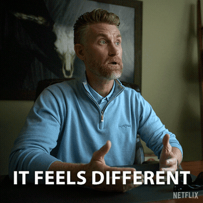 A Man In A Blue Shirt Is Sitting At A Desk With The Words " It Feels Different " Above Him GIF