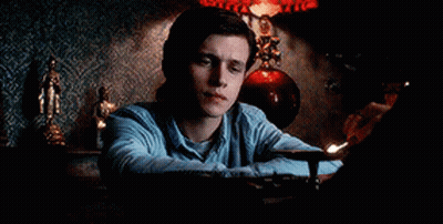 A Man In A Blue Shirt Is Sitting At A Table With A Lamp . GIF