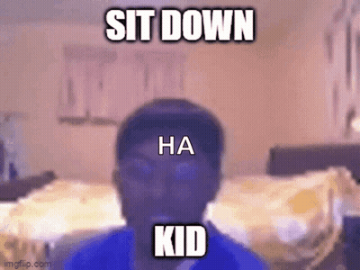 A Man In A Blue Shirt Is Sitting Down In A Bedroom . GIF