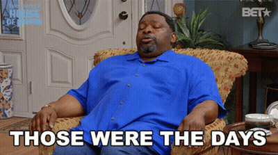 A Man In A Blue Shirt Is Sitting In A Chair With The Words " Those Were The Days " Above Him GIF