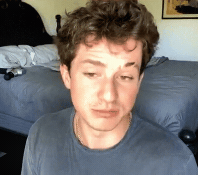 A Man In A Blue Shirt Is Sitting In Front Of A Bed With His Eyes Closed GIF