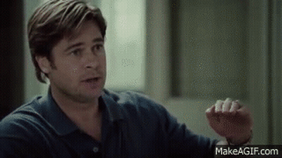 A Man In A Blue Shirt Is Sitting In Front Of A Window Talking To Someone . GIF