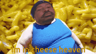 A Man In A Blue Shirt Is Sitting In Front Of Macaroni And Cheese GIF