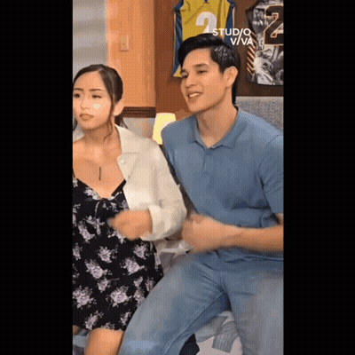 A Man In A Blue Shirt Is Sitting Next To A Woman In A Black And Purple Dress .. GIF