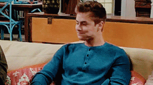 A Man In A Blue Shirt Is Sitting On A Couch GIF