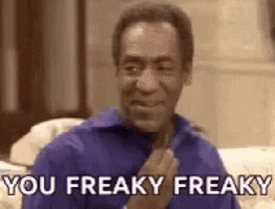 A Man In A Blue Shirt Is Sitting On A Couch And Making A Funny Face . GIF